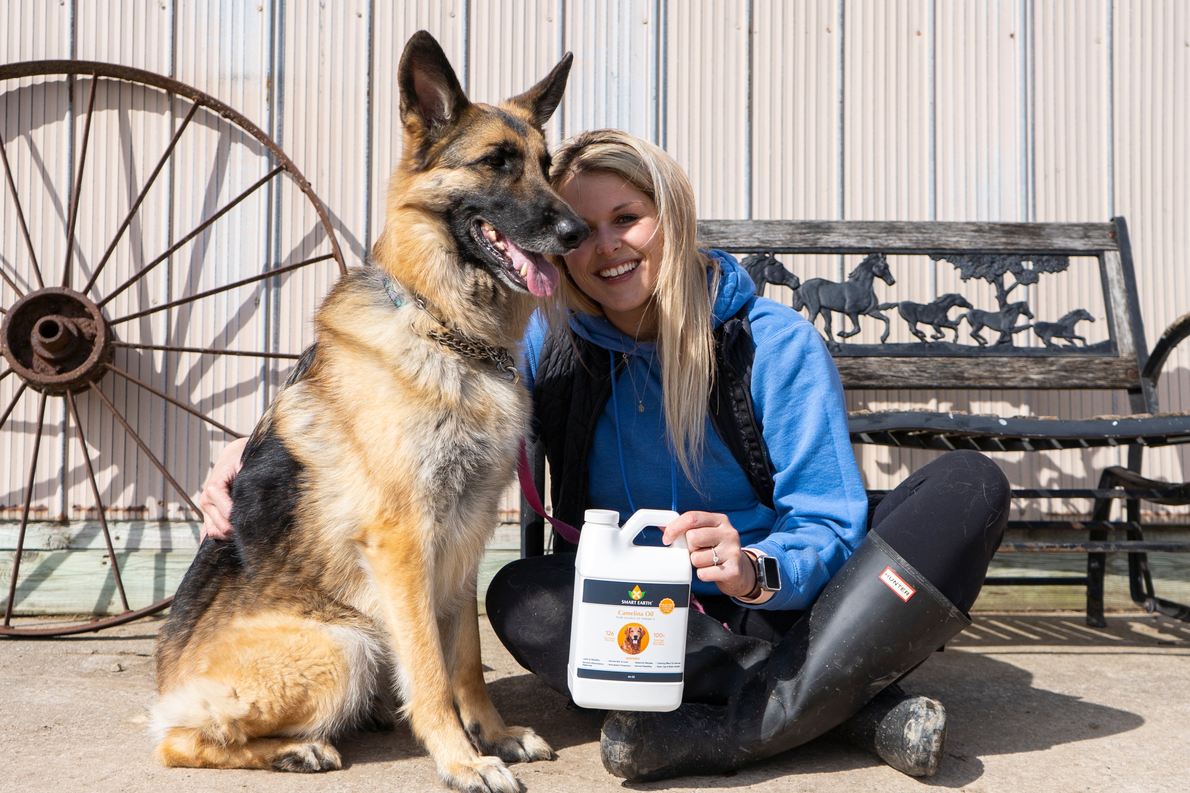 Owner sitting with her German shepherd, holding the 64 oz jug of Smart Earth Camelina Oil