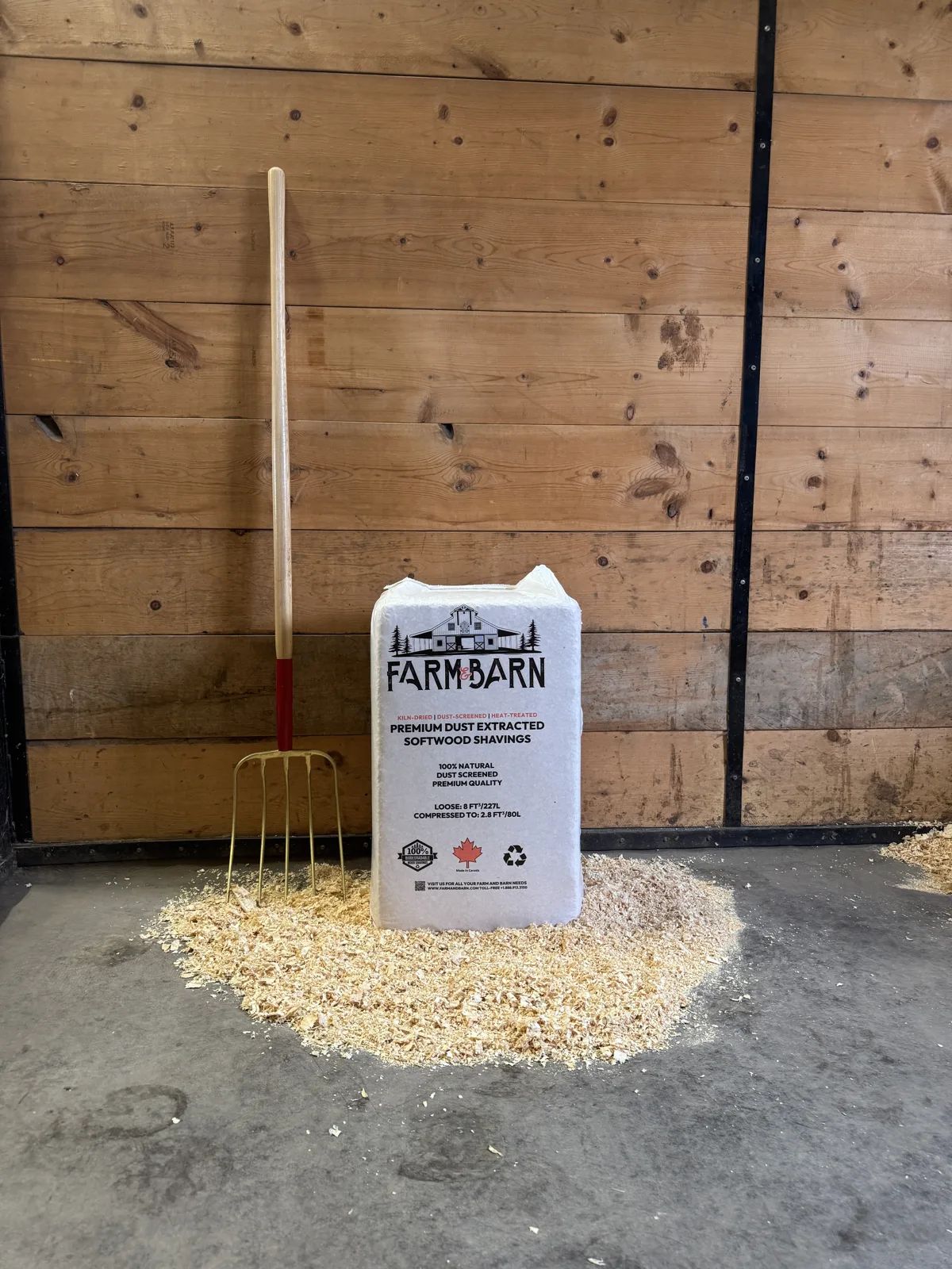 Farm & Barn softwood shavings bag and stall fork next to spread shavings bedding