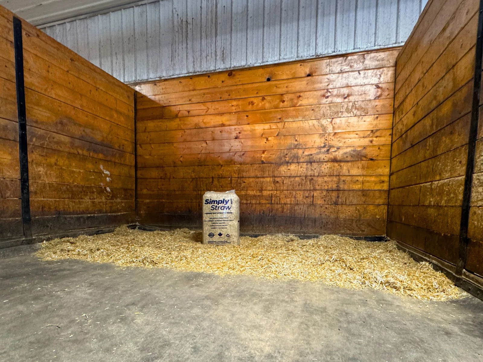 Simply Straw 80 L wheat straw bale in a wood-panelled horse stall bedded with straw